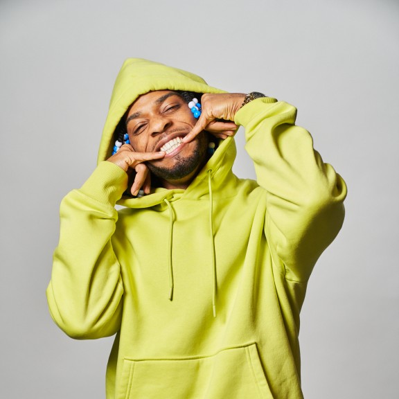black man in a bright yellow hoodie and black pants with a white pattern
