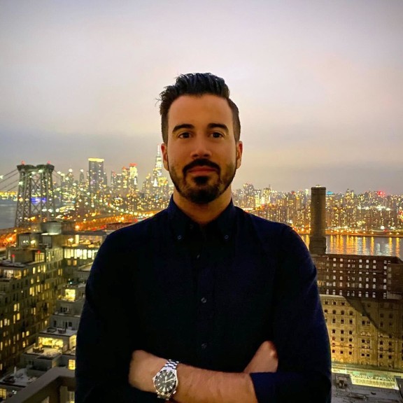 man in a black button shirt with a city skyline in the background 