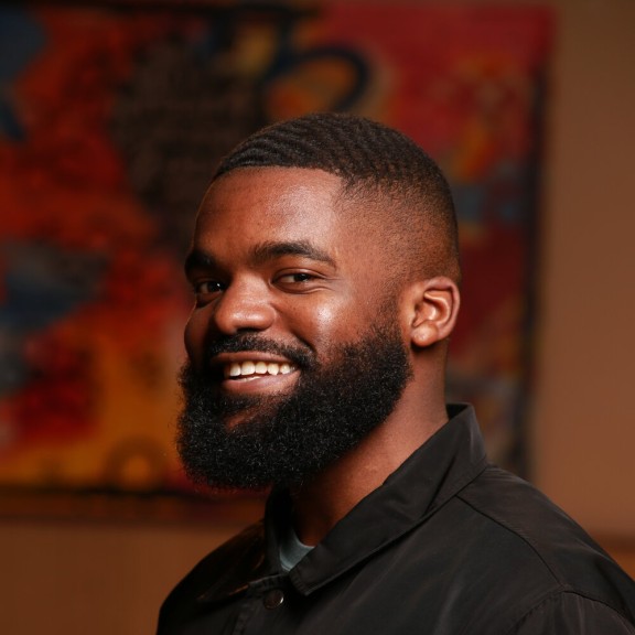 Black man in a black shirt with white words 